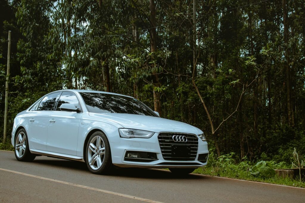 Audi A4 blanche au bord de la route devant une forêt