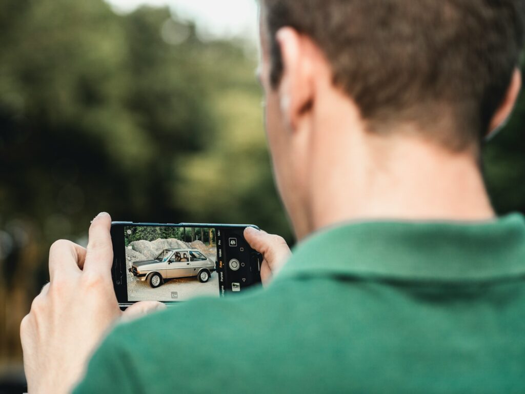 Mann fotografiert ein Auto mit dem Smartphone