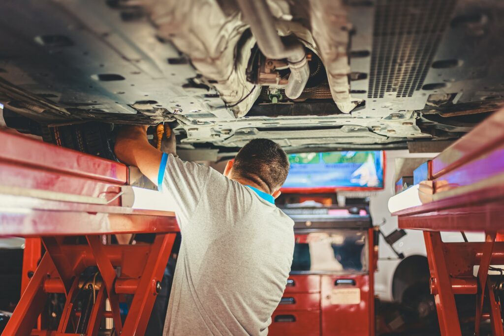 Mechaniker prüft die Unterseite eines Autos auf der Hebebühne