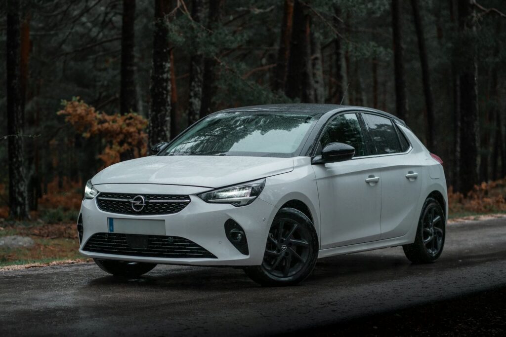Opel Corsa blanche sur une route forestière mouillée par la pluie