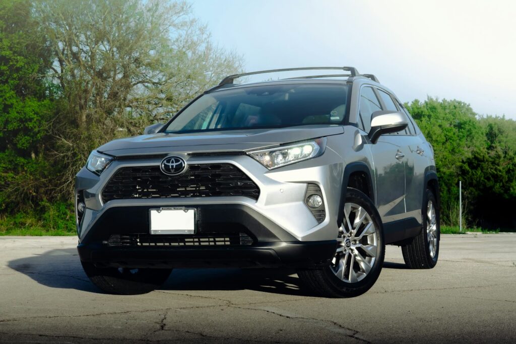 Silberner Toyota RAV4 auf einem Parkplatz vor grünen Bäumen
