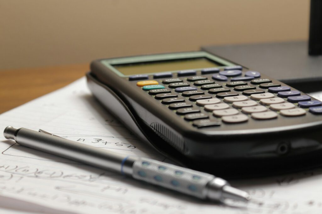 Calculatrice et stylo posés sur des notes manuscrites