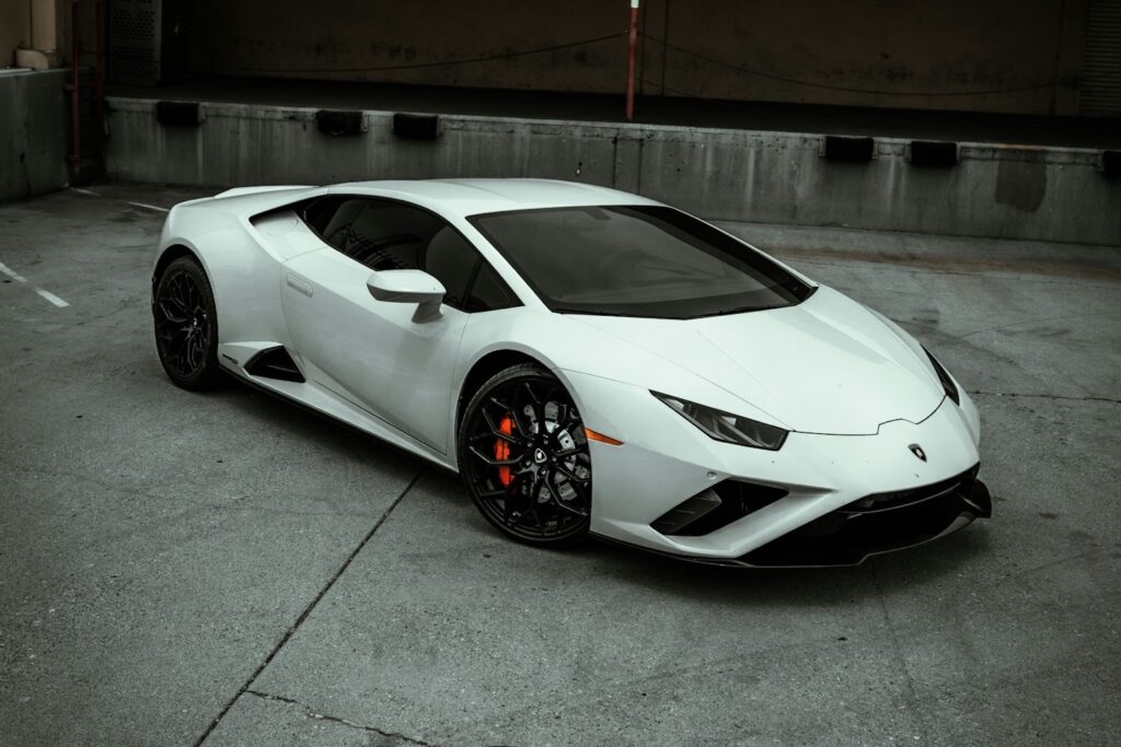 Weisser Lamborghini Huracán von schräg vorne auf einem Betonplatz vor einer Laderampe